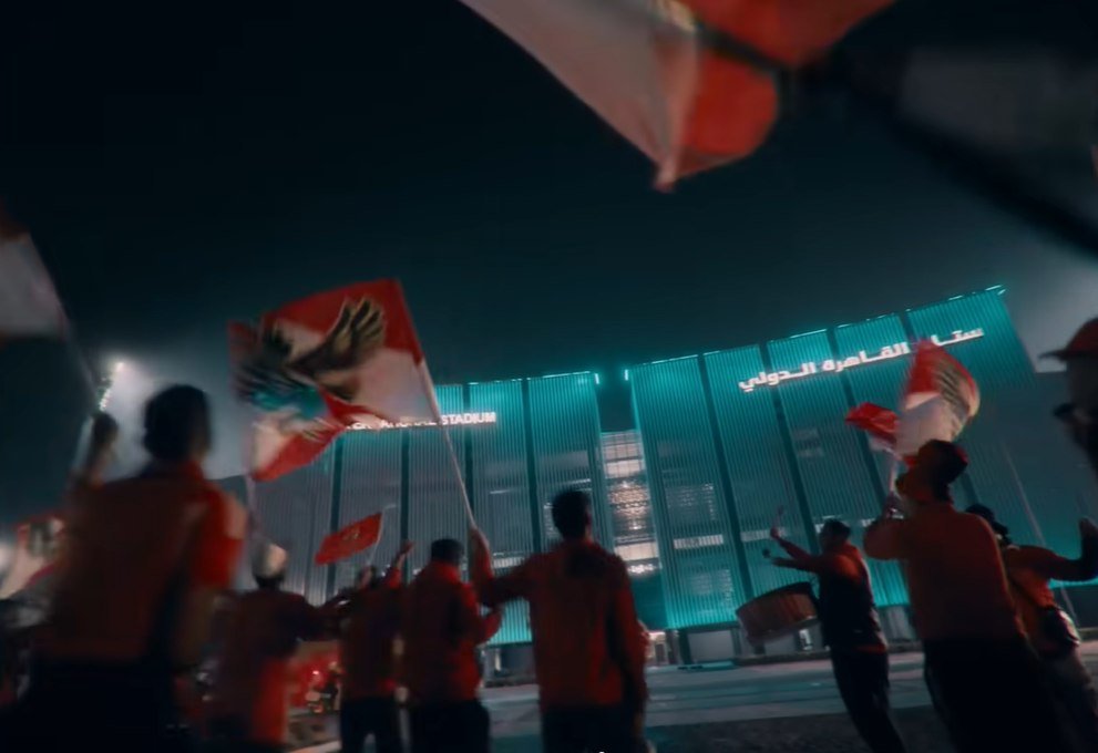 Final film frame — fans with flags outside the stadium
