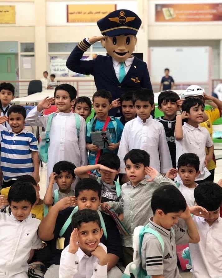 Captain Firnas mascot saluting with schoolchildren